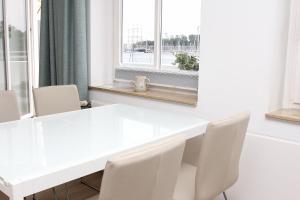 Una mesa y sillas blancas en una habitación con ventana. en Vorderreihe, Fewo 157, en Travemünde