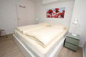 Un dormitorio blanco con una cama con sábanas blancas. en Vorderreihe, Fewo 157, en Travemünde 10 fotos más
