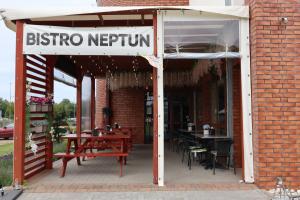 a sign for a restaurant with tables and chairs at Neptun in Kołobrzeg