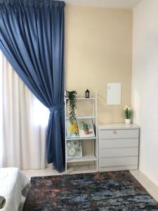 a bedroom with a blue curtain and a dresser at DQis Nest Casa Apartment in Chemor