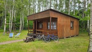 a small wooden cabin with two bikes parked in the grass at Domek w Borkowie nad jeziorem in Borkowo