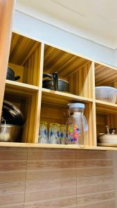 una cocina con armarios de madera con ollas y sartenes en Kampala Studio Apartment1, en Kampala