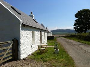 a white building with a fence next to a road at Cnocachanach Cottage in Tarbert