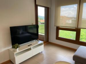salon z telewizorem z płaskim ekranem na białej szafce w obiekcie Apartamentos Lanceata I w mieście A Lanzada