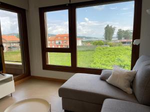 salon z kanapą i dużymi oknami w obiekcie Apartamentos Lanceata I w mieście A Lanzada