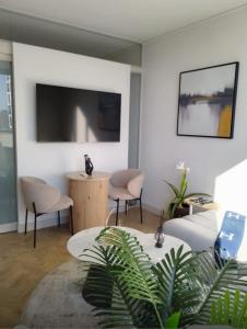 a living room with chairs and a flat screen tv at Dante One Rosebank Apartment in Johannesburg