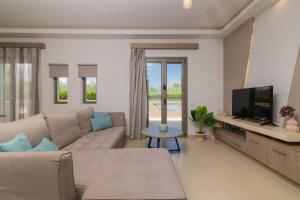 Una sala de estar con un sofá y un televisor. en Villa Vatia 1, en Tragaki