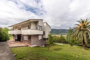 a house with a palm tree in front of it at Aston - Villa Islas Urdaibai in Isla Becoa