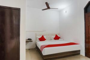 a bedroom with a bed with red pillows and a ceiling fan at Hotel O Gold Stayz in Ballabgarh