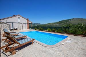 una piscina con 2 tumbonas junto a una casa en Holiday Villa Anna, en Primorski Dolac