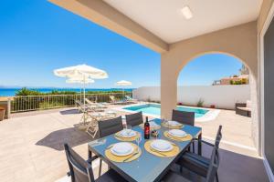 a patio with a table and chairs and a swimming pool at Villa Alora in Barbati