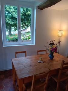 a dining room table with a vase of flowers on it at Le Grenier in Saint-Christophe-sur-Condé +6 photos
