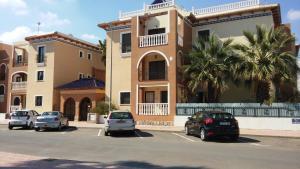 a parking lot with cars parked in front of a building at L.A. Apartment in Los Alcázares