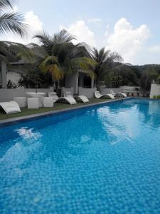 una gran piscina con sillas y palmeras en Fuuka Villa en Pantai Cenang