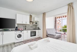 une cuisine avec des armoires blanches et un salon dans l'établissement Loft La Marina in Nerja, à Nerja