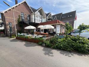 un edificio con tavoli e ombrelloni di fronte di Hotel Orion a Kaag