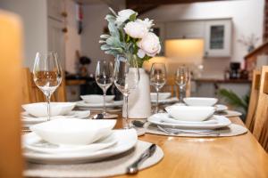 un tavolo con piatti e bicchieri e un vaso di fiori di Treehouse Cottage Spa Retreat a Hereford Altre 35 foto