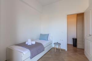 een kleine witte slaapkamer met een bed en een kruk bij Stella by Hospi in Kato Gouves