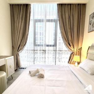 ドバイにあるChic 1BR Apartment with Pool View in Medyanの窓の前にタオル付きのベッド +24枚の写真
