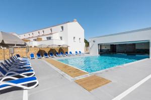 a swimming pool with lounge chairs and a building at Résidence Prestige Odalys Le Domaine des Pins in Noirmoutier-en-l'lle