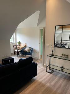 a living room with a black couch and a table at One Bedroom Flat near Bosham & Goodwood in Funtington +9 photos