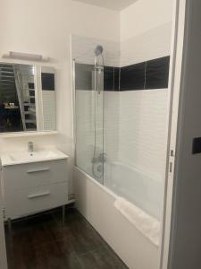 Un baño blanco con ducha y lavabo. en Pleasant Duplex, en Neuilly-sur-Marne