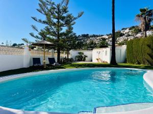 a large swimming pool in a yard with a tree at Casa Laura by Sun & Sea Homes in Moraira