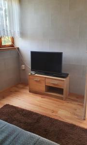 a flat screen tv on a wooden stand in a room at Domek w Borkowie nad jeziorem in Borkowo