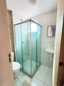 a bathroom with a glass shower and a toilet at Apartamento 100 metros da praia com piscina in Ilhéus +11 photos