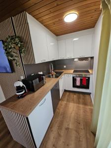 a kitchen with white cabinets and a wooden ceiling at Peak Apartment - Aare Jungfrau AG in Grindelwald