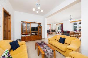 a living room with two yellow couches and a table at Villa Sunset Paradise in Kalavárda