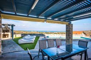 une terrasse avec une table, des chaises et une piscine dans l'établissement Anna Luxury Villa Cretevasion, à Bridgeport