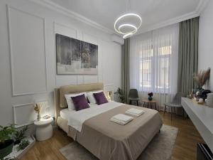 a white bedroom with a large bed with purple pillows at Central Luxury Apartments with Private Garden & Parking in Bucharest