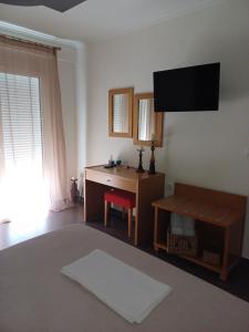 a living room with a desk and a television on the wall at Crystal Aura in Paralia Katerinis