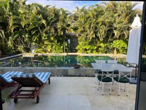 a patio with a table and chairs and a pool at Blue Palm Villa with Private Pool & Tropical Garden in Cap Malheureux