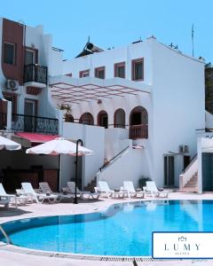 a pool with chairs and umbrellas in front of a building at Bodrum Eskiçeşme Lumy Hotel - Private Pool in Bodrum City