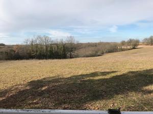 a large field with a large shadow on the ground at Bungalow à la campagne in Hautefage-la-Tour