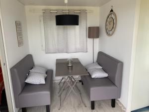a dining room with two chairs and a table and a clock at Bungalow à la campagne in Hautefage-la-Tour