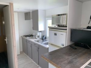 a small kitchen with white cabinets and a counter top at Bungalow à la campagne in Hautefage-la-Tour