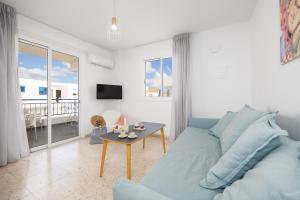 a living room with a blue couch and a table at Latchi Pool Side View Apartment in Lachi