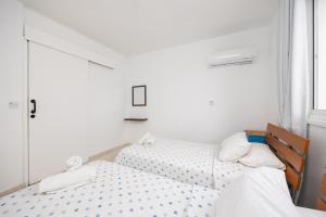 two twin beds in a room with white walls at Latchi Pool Side View Apartment in Lachi +14 photos