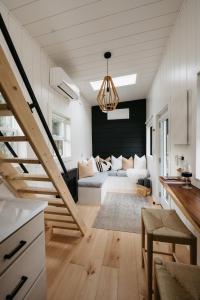 a living room with a couch and a staircase at The Loft - Stargazing Tiny Home with Firepit, Wood Fired Pizza Oven & Movie Projector in Deseronto