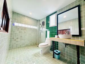 a green tiled bathroom with a toilet and a sink at Baan Khlong Mae Kha Hotel in Chiang Mai