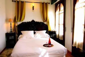 Hotel Merindad de Olite في أوليتي: غرفة نوم بسرير ابيض عليها شمعة حمراء