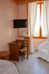 a bedroom with a desk and a bed and a tv at Hôtel l'Hermitage in Brides-les-Bains +29 photos