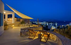a patio with two chairs and a table at night at Villa Mikros Vorias in Karavostasi