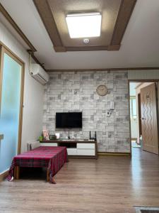 a room with a tv on a brick wall at Suncheon Doran Doran House in Suncheon