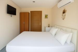 a bedroom with a white bed and a television at Limon Çiçeği Apart in Barbaros