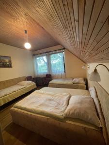 a bedroom with two beds and a wooden ceiling at Hutter Vendégház in Szántód