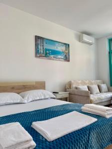 a bedroom with two beds and a couch at Flower Cozy Flat at Santorini Resort in Himare +18 photos